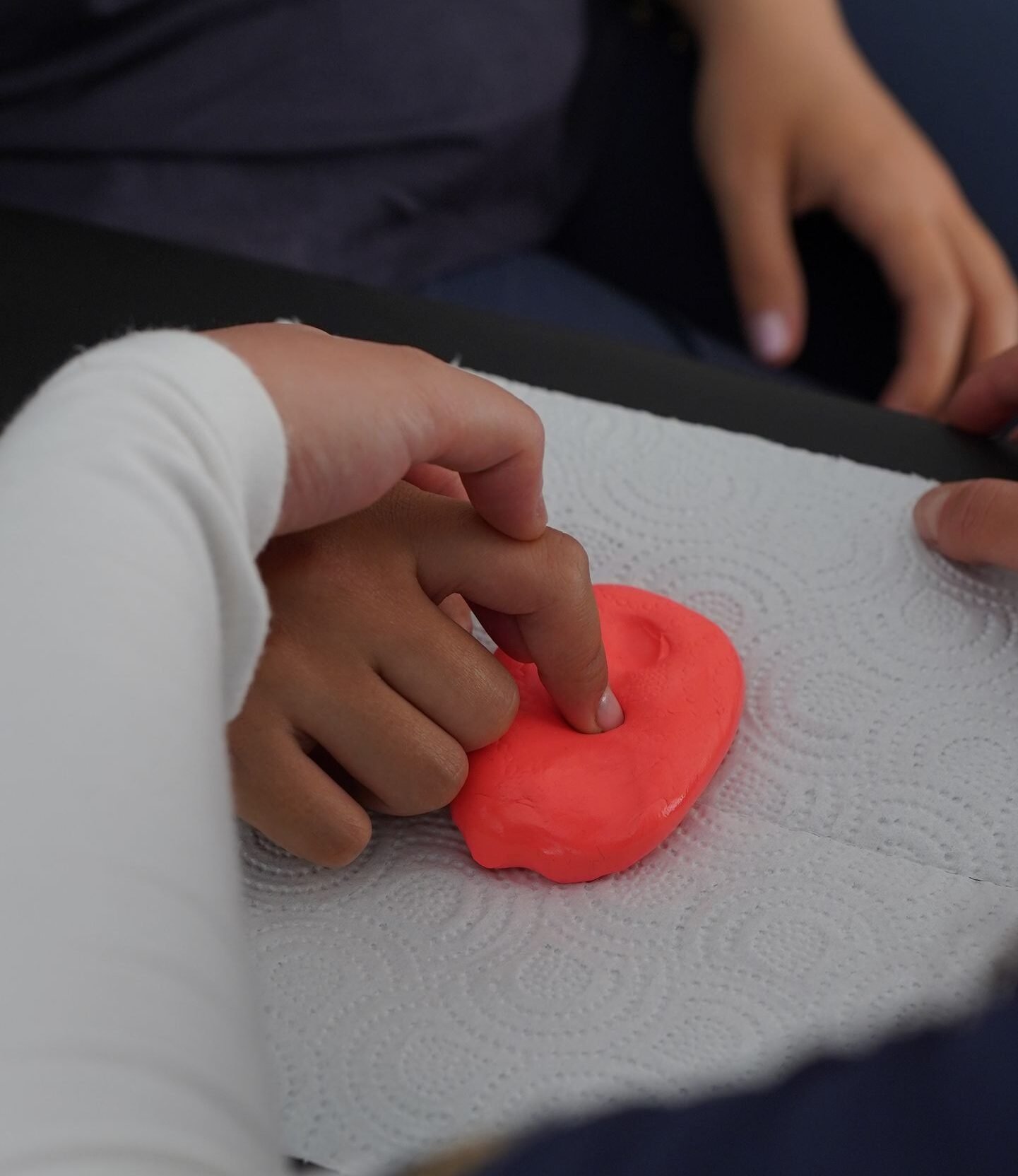 Close-up of hands manipulating putty during therapy session, emphasizing motor skills.